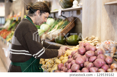 Man shop seller puts potato goods on display case Man shop seller puts potato goods on display case 129539182