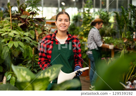 Woman florist withe plastic watering can in floral shop Woman florist withe plastic watering can in floral shop 129539192