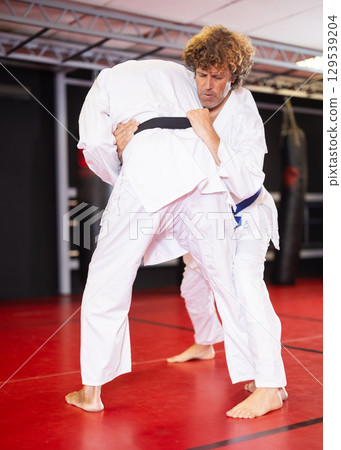 Jiu‑jitsu fighter practicing techniques on red tatami Jiu‑jitsu fighter practicing techniques on red tatami 129539204