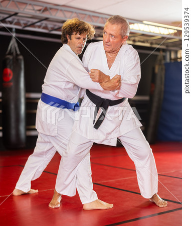 Karate with male athletes practicing, training and sparring in fight class 129539374