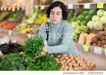 Adult woman chooses parsley in vegetable shop 129539381