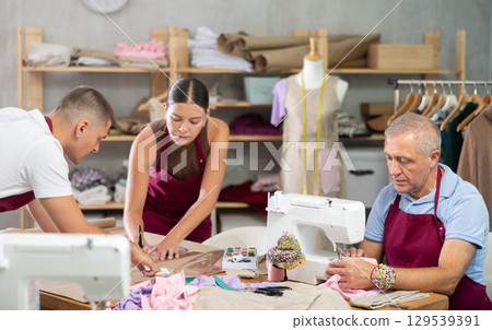 Senior man employee sewing, stitch clothes, girl work with mannequin, guy draw dress pattern 129539391