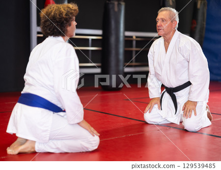 Karate sensei and student kneeling in seiza on dojo tatami Karate sensei and student kneeling in seiza on dojo tatami 129539485