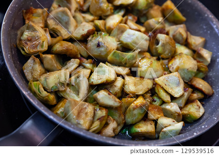 Fried peeled artichokes in a pan 129539516