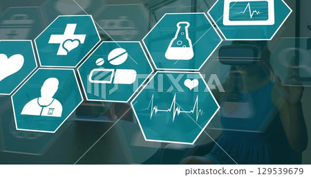 Image of medical icons over women using vr headset 129539679
