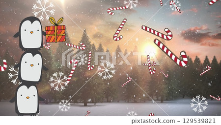 Image of tower of three penguins with christmas gift, snow and candy canes over winter landscape Image of tower of three penguins with christmas gift, snow and candy canes over winter landscape 129539821
