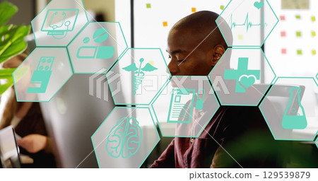 Image of scientific icons in hexagons over african american male scientist using computer 129539879