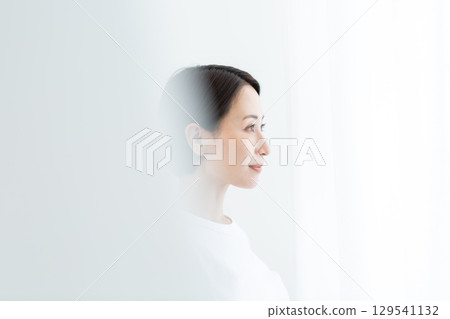 Profile of a woman with a clear look gazing ahead in the light Profile of a woman with a clear look gazing ahead in the light 129541132