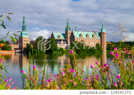 Frederiksborg Castle and the water mirror seen through the flowers on the shore of Lake Pallassee in Hillerød near Copenhagen, Denmark, Northern Europe 129541173