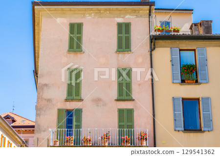 Windows with green wooden shutters. Flowers in pot on balcony. Italy summer day. Italian style facade 129541362