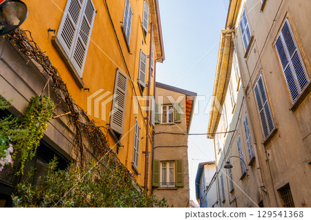 Narrow Italian street in Como city. Multicolor old yellow house building architecture Narrow Italian street in Como city. Multicolor old yellow house building architecture 129541368