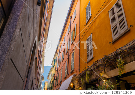 Narrow Italian street in Como city. Multicolor old house building architecture. Window shutter Narrow Italian street in Como city. Multicolor old house building architecture. Window shutter 129541369