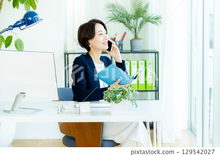在辦公室使用智能手機的女商人 在辦公室使用智能手機的女商人 129542027