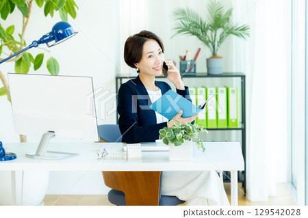在辦公室使用智能手機的女商人 在辦公室使用智能手機的女商人 129542028