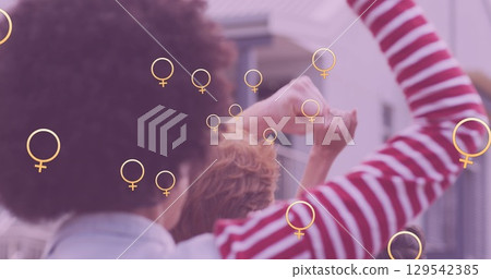 Image of falling women symbols over two diverse women raising fists Image of falling women symbols over two diverse women raising fists 129542385