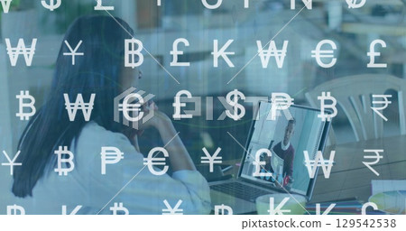 Image of currency symbols over woman having image call on laptop 129542538