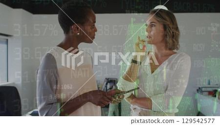 Image of financial data and graphs over diverse female coworkers in office 129542577