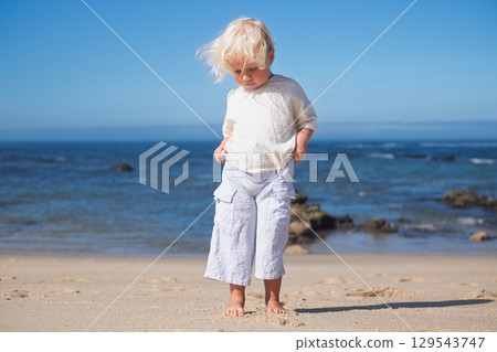 Little blonde European girl walking on an empty sandy beach in Portugal 129543747