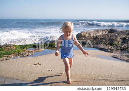 Girl Playing on the Beach During Vacation Girl Playing on the Beach During Vacation 129543783