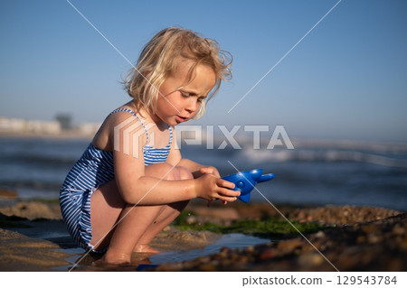 Girl Playing on the Beach During Vacation Girl Playing on the Beach During Vacation 129543784