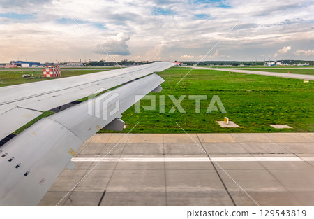 View of airplane wing, blue skies and green land during landing. Airplane window view. View of airplane wing, blue skies and green land during landing. Airplane window view. 129543819