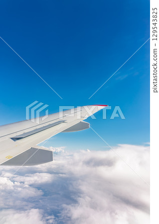 View from the airplane window at a beautiful cloudy sky and the airplane wing View from the airplane window at a beautiful cloudy sky and the airplane wing 129543825