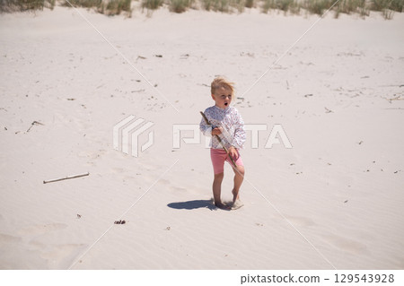 Little Girl Playing Alone in the Sand on the Beach Little Girl Playing Alone in the Sand on the Beach 129543928