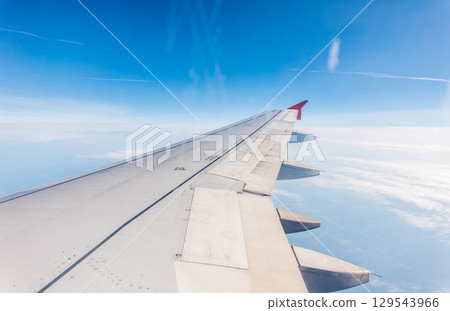 View from the airplane window at a beautiful cloudy sky and the airplane wing 129543966