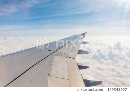 View from the airplane window at a beautiful cloudy sky and the airplane wing 129543967