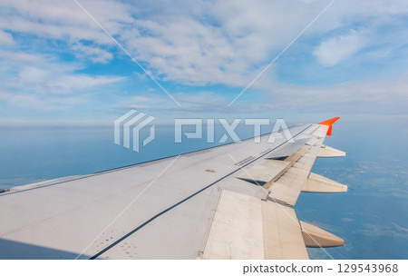 View from the airplane window at a beautiful cloudy sky and the airplane wing 129543968