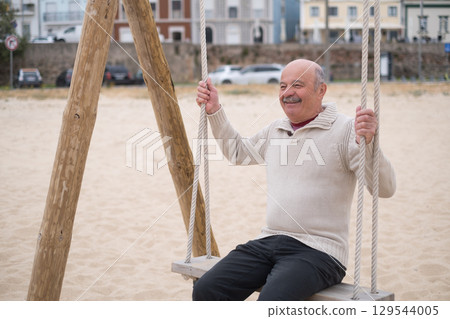 An elderly person swinging on a swing, reminiscing about childhood. An elderly person swinging on a swing, reminiscing about childhood. 129544005