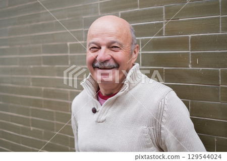 Elderly Spanish Man Standing by a Wall and Smiling 129544024