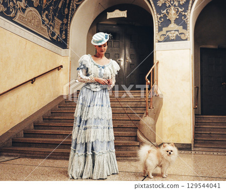 Elegant woman in blue dress with white fluffy Pomeranian dog outdoors 129544041
