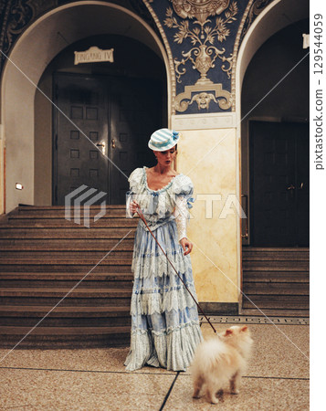 Elegant woman with fluffy Pomeranian dog near arched doorway 129544059