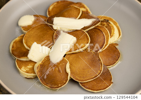 a large pile of round pancakes with butter made from milk after cooking, hot pancakes with butter that melts 129544104