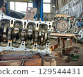 A disassembled car engine in a repair shop. 129544431