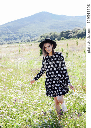 woman in summer dress and hat on a field of daisy flowers 129545508