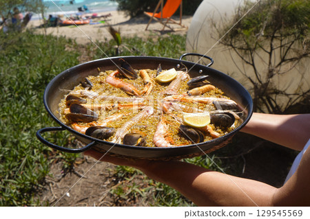 a seafood paella in front of the beach 129545569