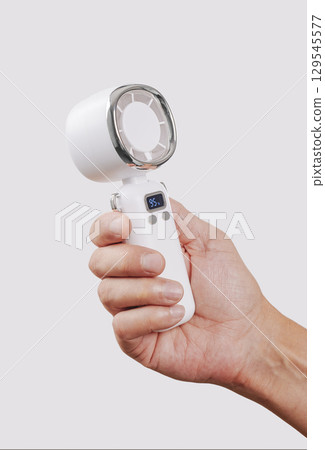 close-up of a man cooling himself with a white fan 129545577