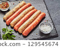 Raw butchers sausages on slate with herbs. Overhead view 129545674