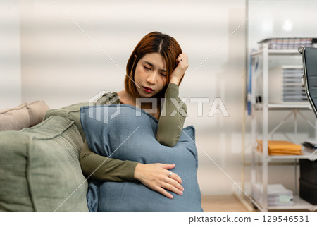 Woman sitting in sofa holding pills, having stress, boredom, loneliness, anxiety. 129546531