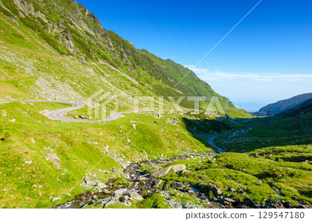 landscape with transfagarasan road in summer. travel romania. scenic view of valley with steep rocky hills and water stream on a sunny morning. alpine scenery of transylvania 129547180