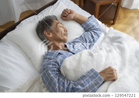 Middle-aged man sleeping in bed 129547221