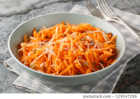 Juicy carrot apple salad with raisins with lemon dressing close-up in a bowl. horizontal Juicy carrot apple salad with raisins with lemon dressing close-up in a bowl. horizontal 129547299