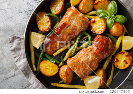 Baked Lemon garlic Pork Tenderloin with french beans and new Potatoes close-up in a pan. Horizontal top view Baked Lemon garlic Pork Tenderloin with french beans and new Potatoes close-up in a pan. Horizontal top view 129547305
