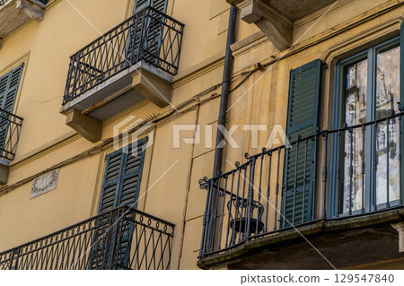 Windows with wooden shutters. Balcony in Italian style facade house architecture Windows with wooden shutters. Balcony in Italian style facade house architecture 129547840