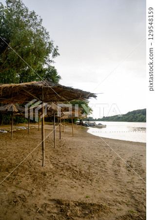 River bank with beach umbrellas and trees 129548159