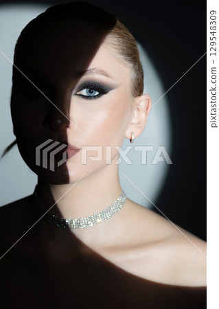 Beautiful woman with fancy jewelry and evening makeup portrait illuminated with bright round studio light Beautiful woman with fancy jewelry and evening makeup portrait illuminated with bright round studio light 129548309