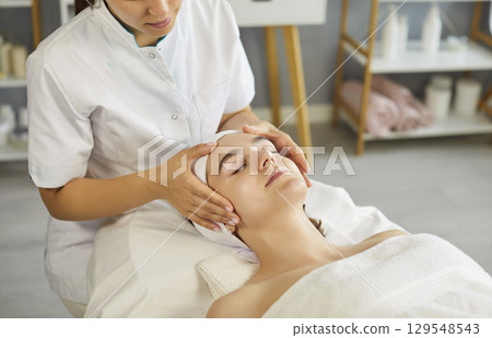 Facial massage of woman for skin rejuvenation, lifting and spa relax of woman by cosmetologist 129548543