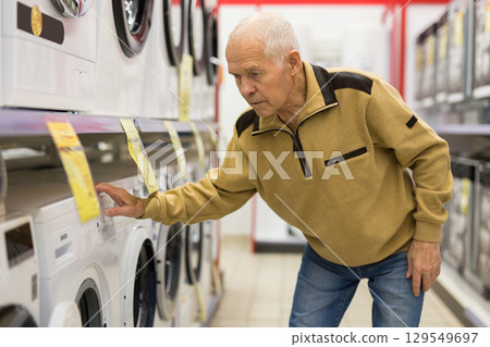 senor man pensioner buying washing machine in showroom of electrical appliance store senor man pensioner buying washing machine in showroom of electrical appliance store 129549697